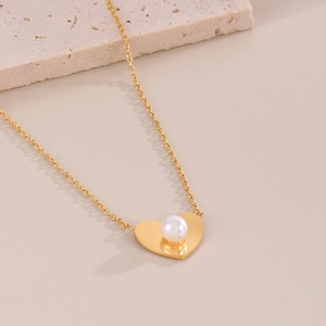 Detailed view of a gold heart pendant necklace with shell pearl on textured background