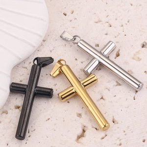 Detailed view of cross pendants in black, gold, and silver finishes on a stone texture