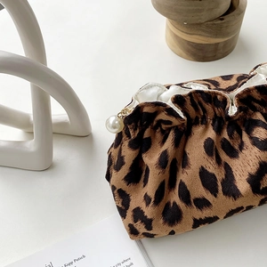 Detail of leopard print makeup bag with drawstring closure and elegant pearl pendant accessory