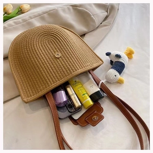 Detail view of brown woven straw bag interior showing storage space and leather strap