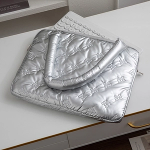 Detail of silver quilted laptop bag featuring bow pattern and padded handles