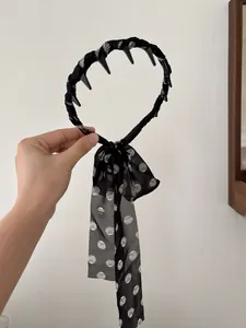 Detail of a black hairband with a long black and white polka dot chiffon ribbon bow
