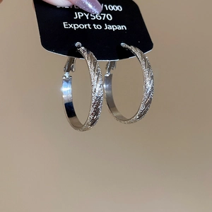 Macro detail of silver 925 hoop earrings with twill frosted texture and pin closure