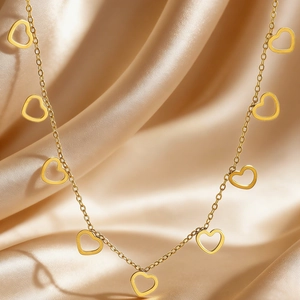 Detail of golden stainless steel necklace with multiple heart charms on satin fabric