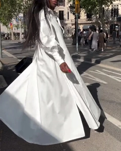 Détail d'une robe chemise en satin blanc avec ourlet fendu fluide dans la rue