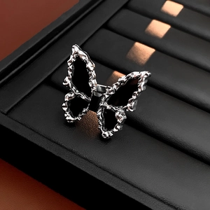 Macro shot of silver butterfly ring featuring black gemstone and lava texture finish