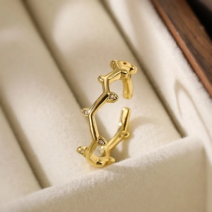 Macro detail of irregular wave gold ring with zircon accents in a beige velvet gift box