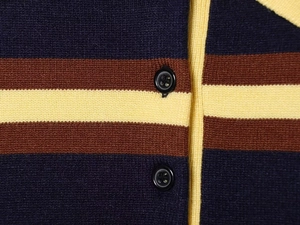 Detail shot of multi-color striped knit sweater with black round buttons and ribbed texture