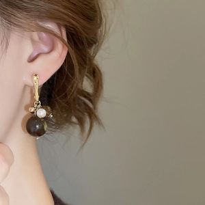 Detail shot of vintage earrings with a pearl and amber acrylic bead on gold hooks