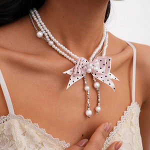 Detail of multi-layer pearl choker with pink polka dot ribbon bow and sparkling crystals