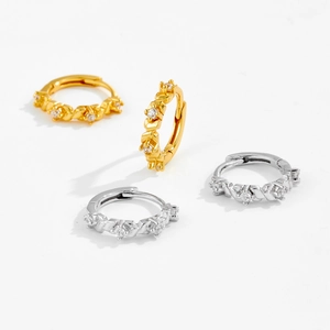 Detail of silver and gold geometric hoop earrings with sparkling inset gemstones