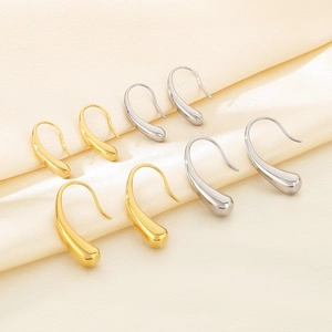 Polished water-drop metal earrings in gold and silver finish on champagne silk