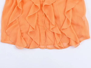 Detail of ruffled chiffon blouse hem and matching buttons in bright orange fabric