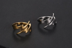 Detailed view of silver and gold lightning-shaped stainless steel rings on a dark surface