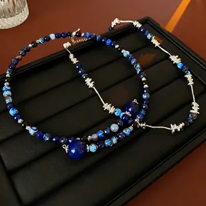 Dual blue beaded necklaces with silver tube accents on luxury jewelry display tray