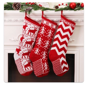 Three knitted Christmas stockings with reindeer and tree patterns hung on fireplace
