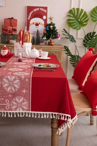 Close-up of red Christmas tablecloth featuring snowflake jacquard patterns and white fringe