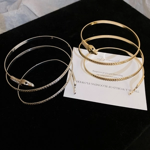 Detailed close-up of gold and silver snake coil bracelets with diamond scales and black eyes