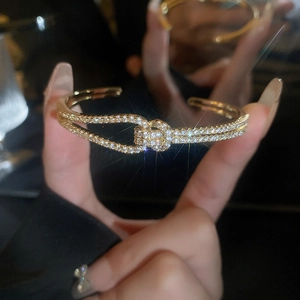Detail van gouden knooparmband met pavé-zirkonen en een schitterend stereffect in het donker