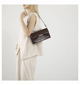Vue détaillée d'un sac bandoulière vintage en cuir marron foncé sur un mannequin