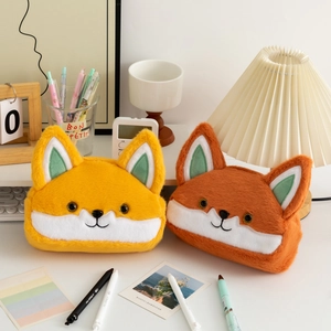 Detail of plush fox pencil cases in yellow and brown on a desk with cute stationery