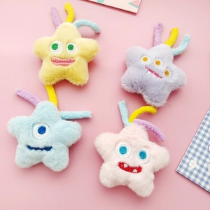 Dettaglio di spille a forma di stella in peluche colorate con visi ricamati