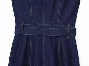 Detailed macro view of deep indigo denim fabric with yellow contrast stitching and belt loops