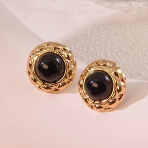 Detailed macro view of vintage gold-plated round stud earrings with black resin inlay