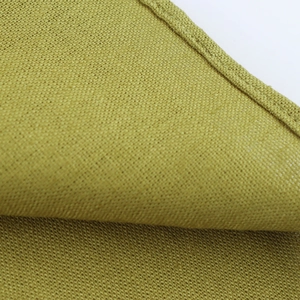 Detailed close-up of yellow-green linen fabric texture and neat stitching on dress