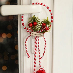 Christmas door hanger with greenery and red berries on a white handle with warm bokeh lights