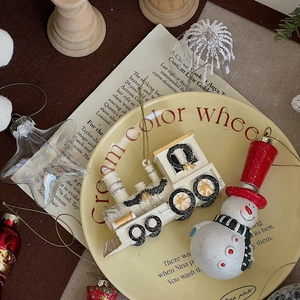Close-up of glittery white train and snowman Christmas ornaments on a cream plate