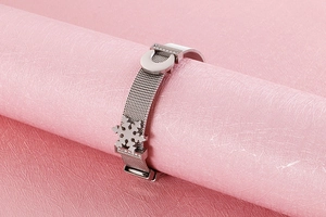 Dettaglio del bracciale in maglia d'acciaio con ciondoli a forma di fiocco di neve e luna