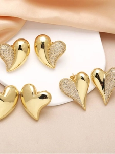 Detailed view of heart-shaped gold-plated stud earrings with pavé zircon on pink silk