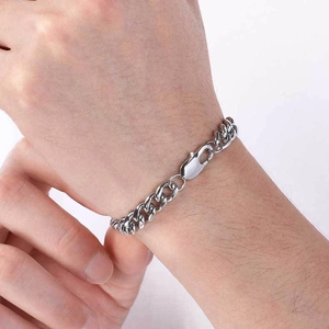 Gros plan d'un bracelet gourmette argenté avec fermoir mousqueton porté au poignet