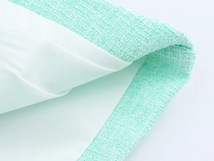 Gros plan sur la texture du tweed vert menthe et la doublure blanche aux coutures fines