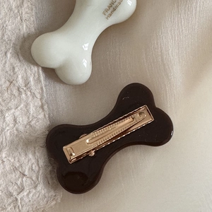 Detail of bone-shaped hair clips in black and white with engraved handmade lettering