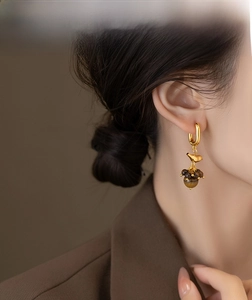Detail of 18k gold plated bird earring with tiger eye tassels on model's ear