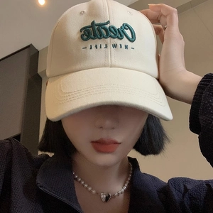 Beige cotton baseball cap with green Create New Life embroidery worn by a model