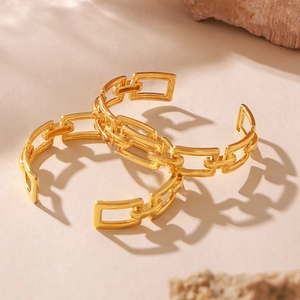 Pair of 18k gold plated hollow chain link open bracelets on a minimalist stone surface