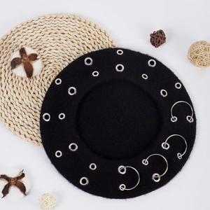 Detail shot of black wool beret with metal eyelets and rings on rustic background
