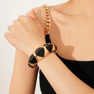 Retro wide open bangle featuring black enamel drip glaze on a gold metal band