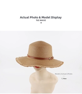 Detail of brown straw hat featuring a leather strap with gold buckle and frayed brim