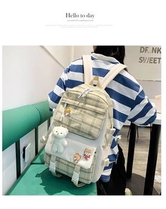 Detail of cute plaid canvas backpack with plush bear charm and cartoon badges