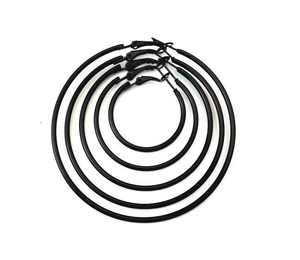 Macro view of multiple sizes of matte black hoop earrings nested on a white background