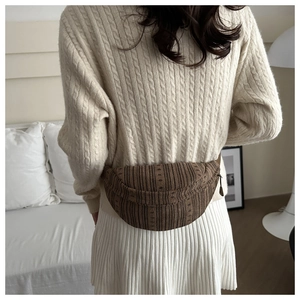 Close-up of brown corduroy crossbody bag texture on a model wearing an ivory sweater
