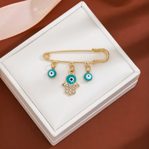 Detail of gold brooch with blue evil eye charms and Hand of Fatima in a gift box