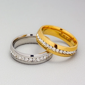 Close-up of overlapping gold and silver stainless steel rings with a row of inlaid zircon