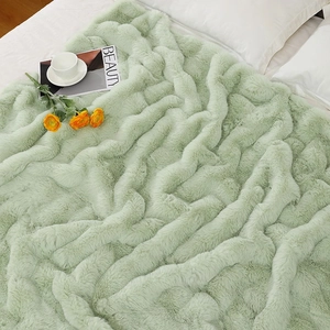 Detailed texture of thick light green faux fur blanket on a cozy bed setup