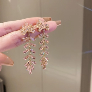 Vue détaillée de boucles d'oreilles à pompon rose avec fleurs dorées et strass