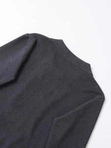 Close-up of the fine knit texture and shoulder seam on a dark grey knit sweater